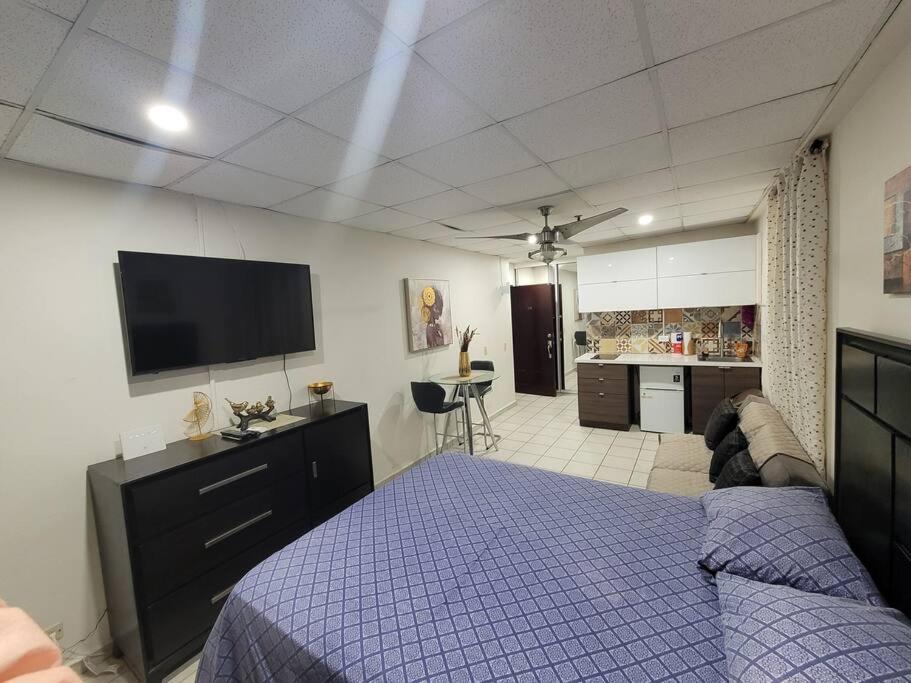 1 dormitorio con 1 cama y TV de pantalla plana en Cocomar Beach Studio, en San Juan