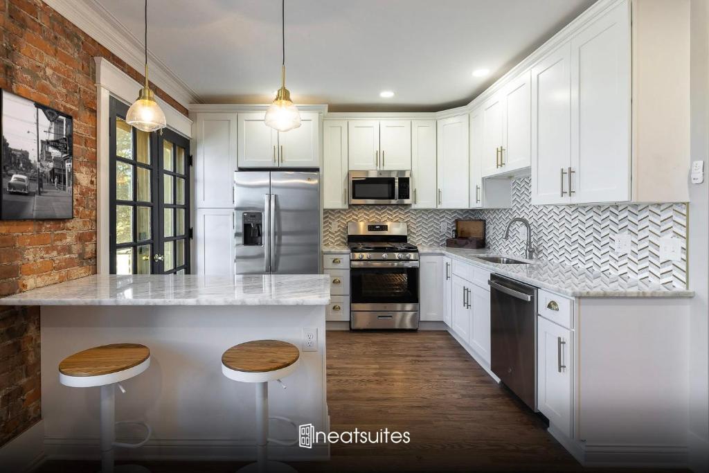 eine Küche mit weißen Schränken und weißen Arbeitsplatten in der Unterkunft The Gilded Cincy-View Condo in Covington