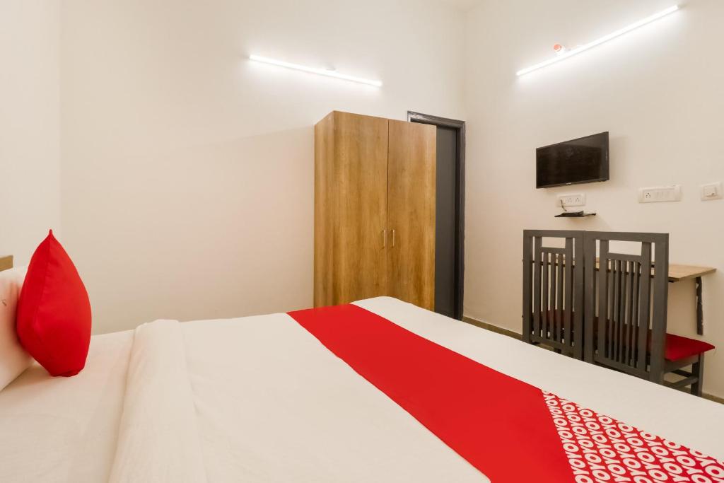 um quarto com uma cama com almofadas vermelhas e uma televisão em Perky Stay em Faridabad