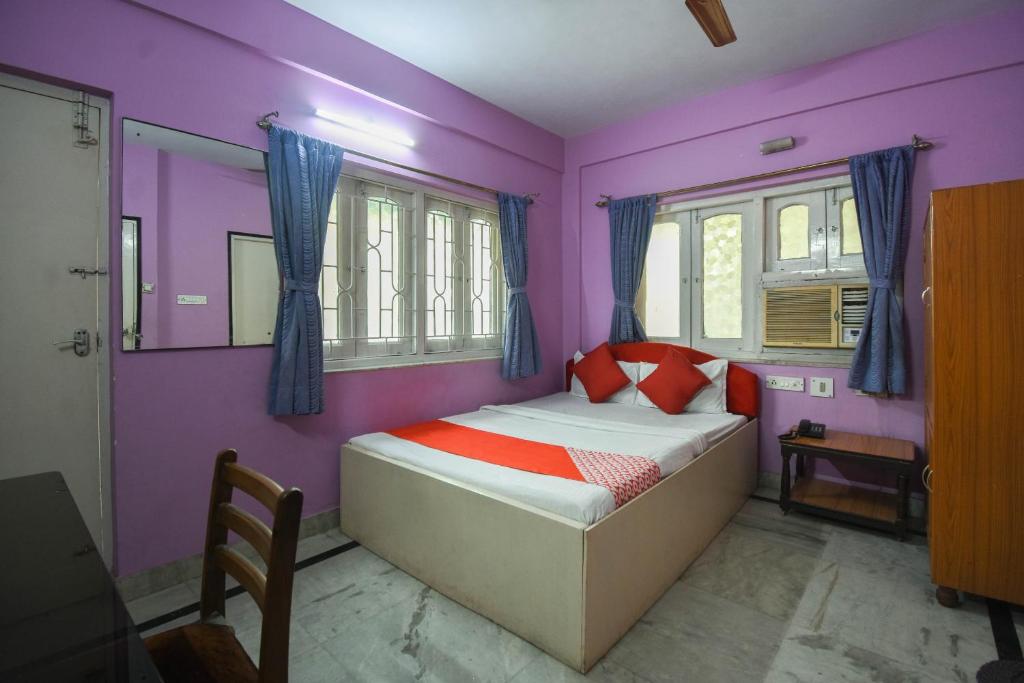 sypialnia z fioletowymi ścianami i łóżkiem z czerwonymi poduszkami w obiekcie OYO Balaji Inn w mieście Ballygunge