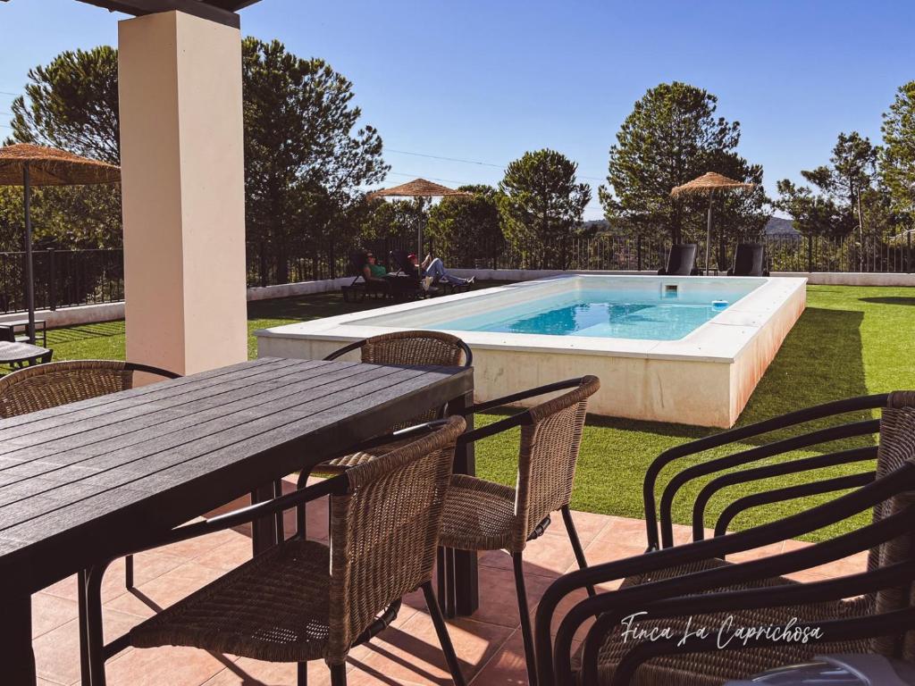 un patio con mesa, sillas y piscina en Finca La Caprichosa, en Cortelazor