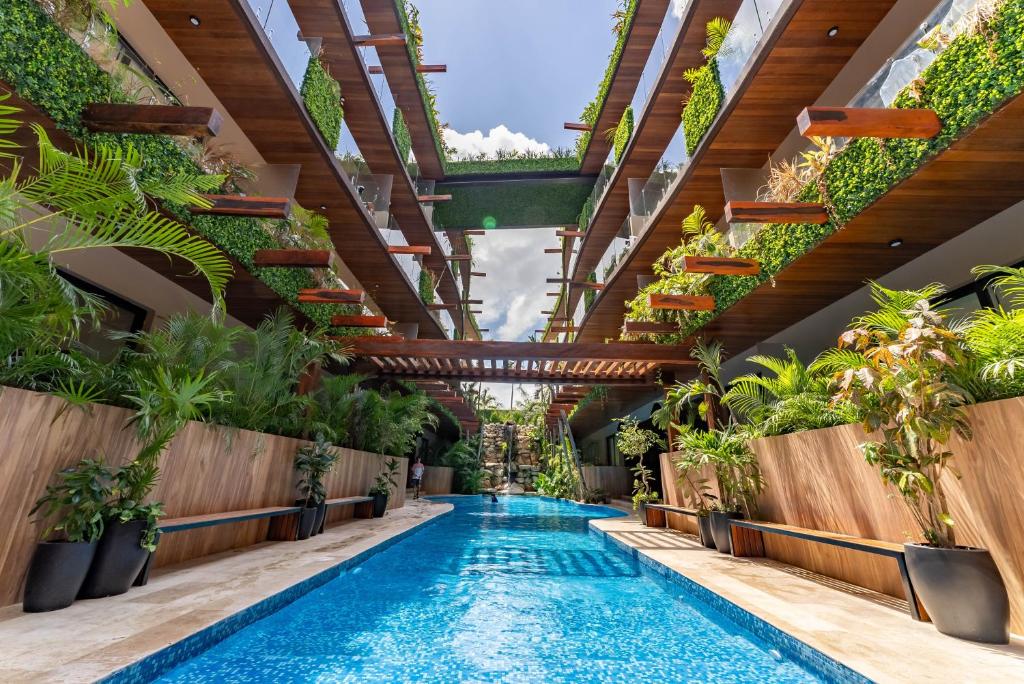 a swimming pool with plants in a building at Menesse Apartments in Tulum