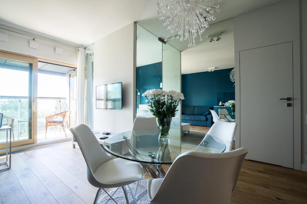 a dining room with a glass table and white chairs at VipWarsawApartments Sapphire Mennica Residence in Warsaw