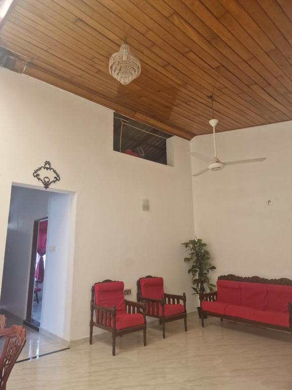a living room with red chairs and a wooden ceiling at Perivale in Moratuwa