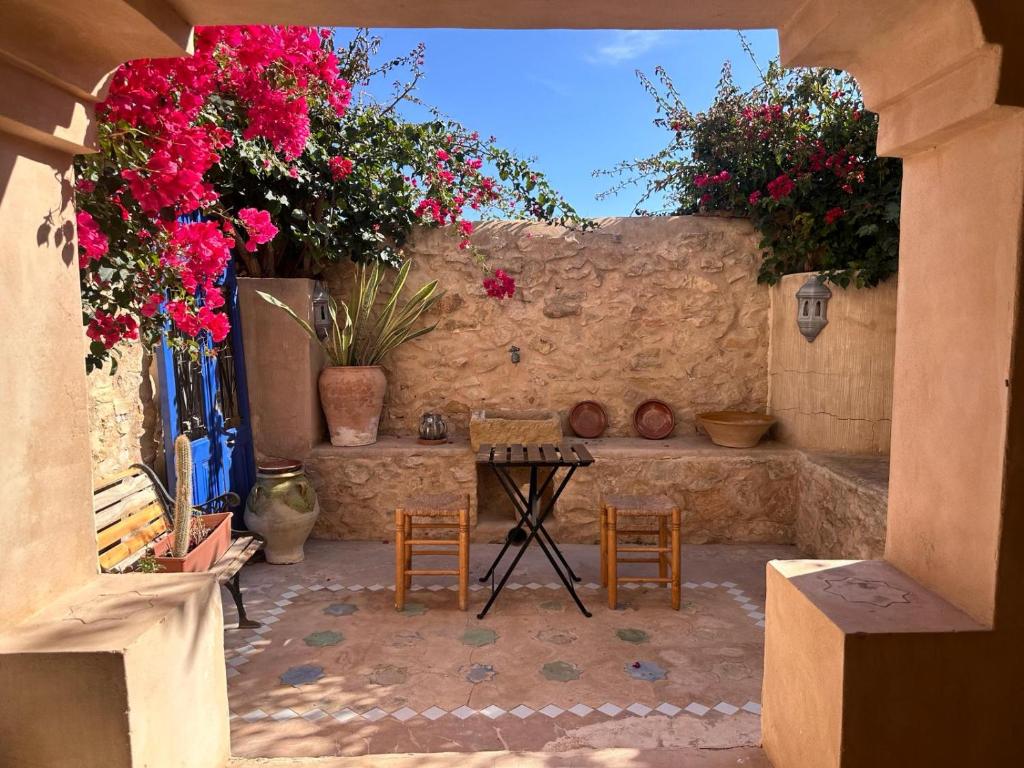 um pátio com uma mesa, cadeiras e flores em Escapada mágica en El Carmen em Aigues