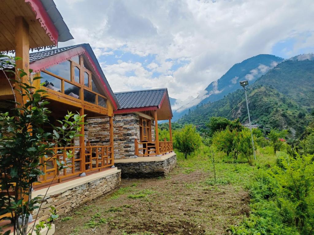 une cabane dans les montagnes avec des montagnes en arrière-plan dans l'établissement Cliff Haven Tirthan, à Banjār