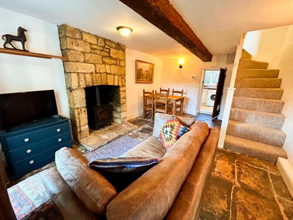 a living room with a couch and a stone fireplace at Crown Cottage - Charming 2 Bed Cottage in Dudbridge