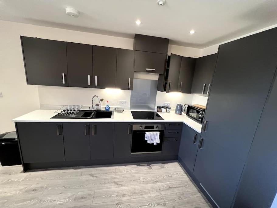 a kitchen with black cabinets and a sink at Spacious One Bedroom Apartment in Hemel Hempstead