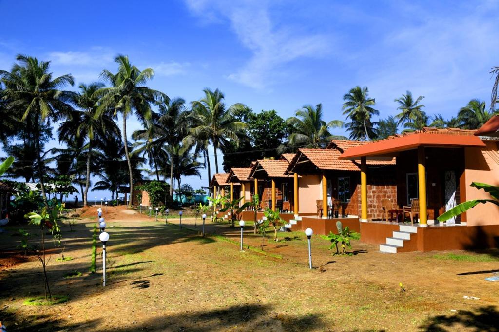 a house with palm trees in front of it at Niyam Beach Stay in Gokarna