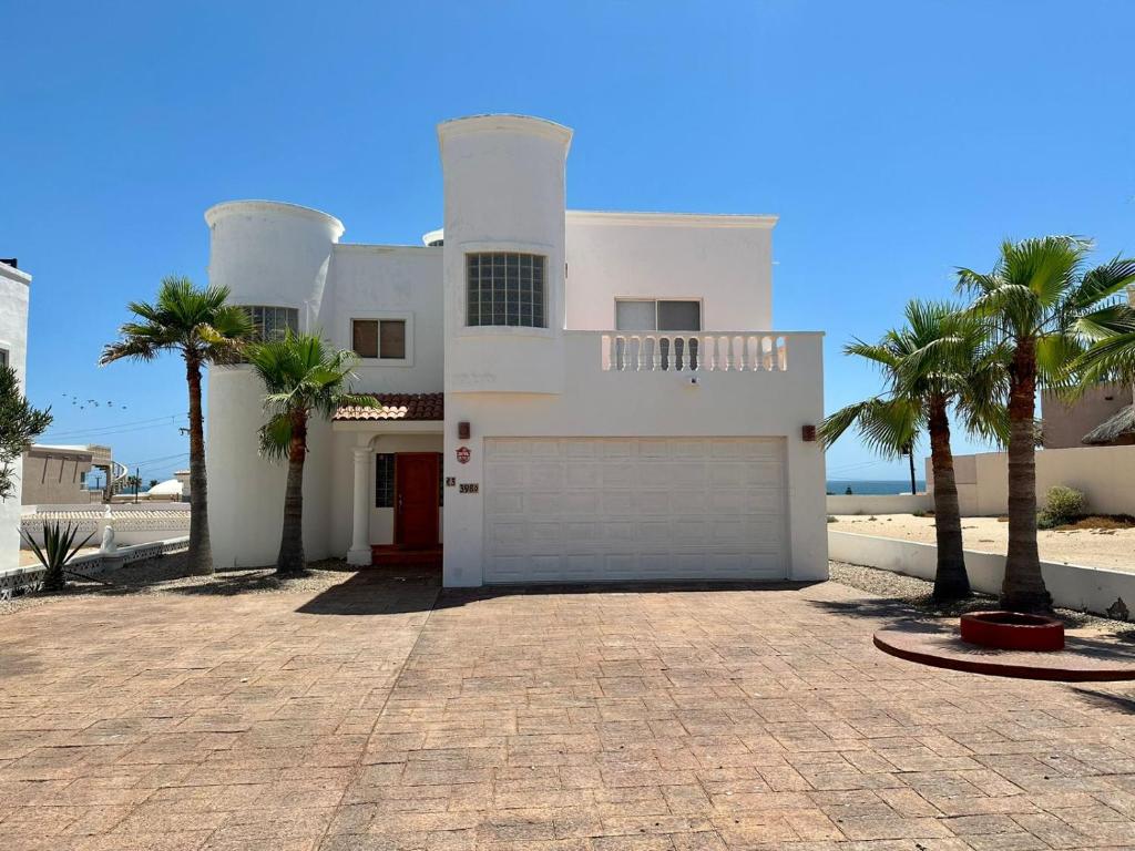 a white house with palm trees in front of it at Casa del Sol by FMI Rentals in Puerto Peñasco