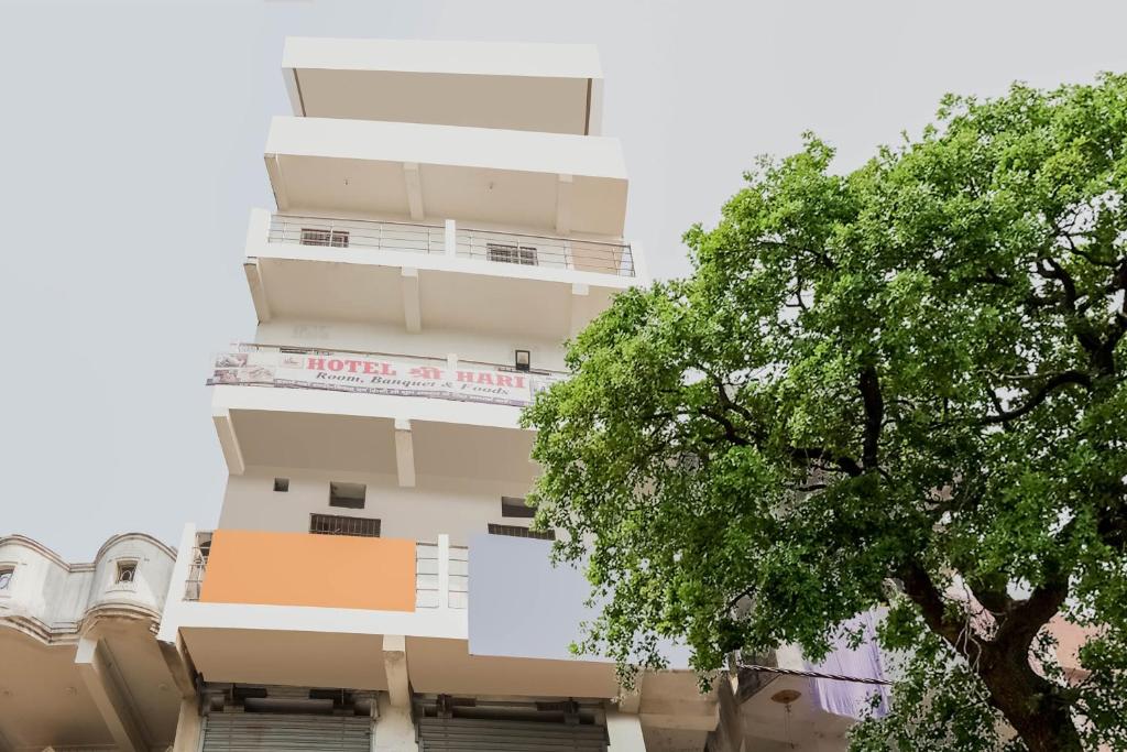 un edificio alto con un árbol delante de él en OYO Hotel Sri Hari en Bihta