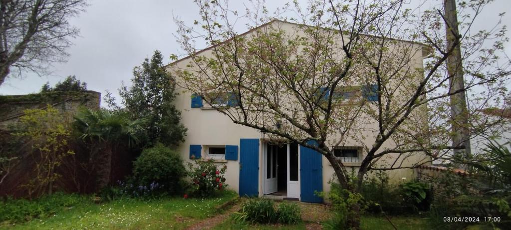 een wit huis met blauwe deuren en een boom bij Maison pour 10 personnes au centre à St Georges in Saint-Georges-dʼOléron