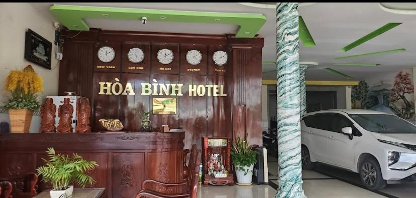 un hôtel avec une voiture garée devant lui dans l'établissement Khách sạn Hoà Bình, à Cà Mau