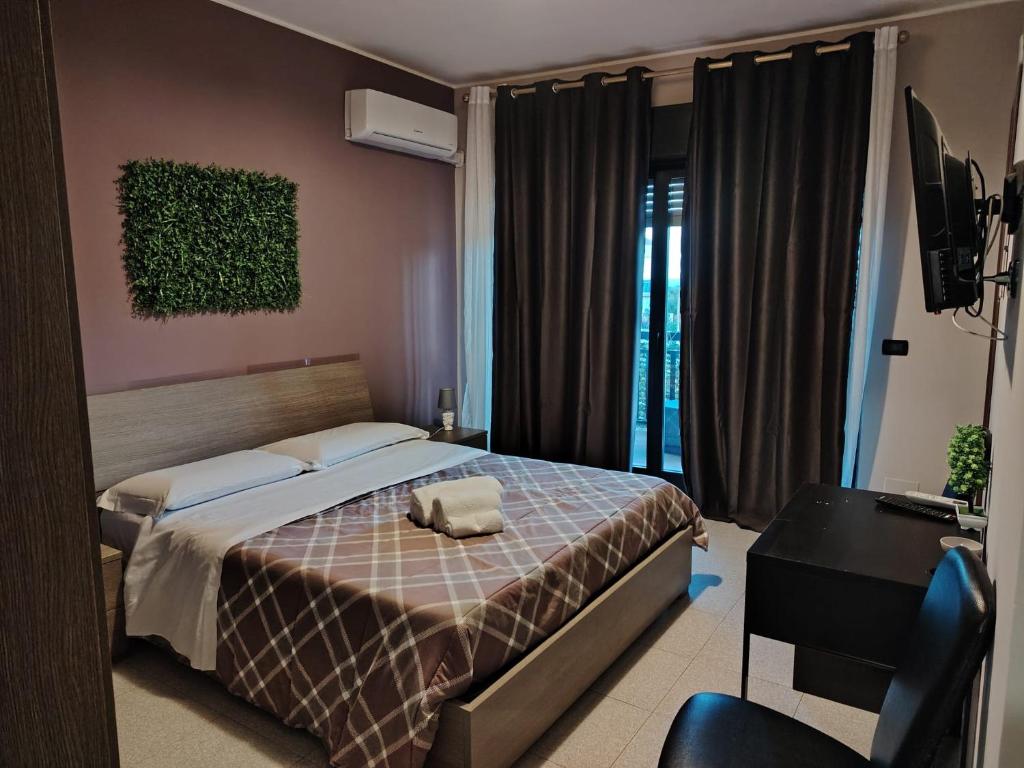 sypialnia z łóżkiem, biurkiem i telewizorem w obiekcie Calipso Bed&Breakfast w Katanii