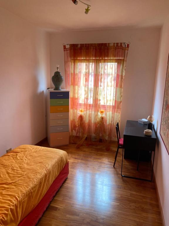 - une chambre avec un lit, un bureau et une fenêtre dans l'établissement Appartamento ad Acilia, à Acilia