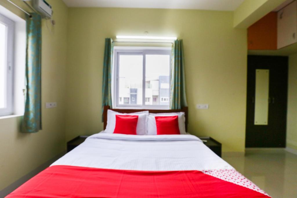 Schlafzimmer mit einem Bett mit roten Kissen und einem Fenster in der Unterkunft OYO Shriram Residency in Chennai