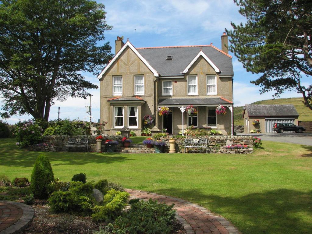 une grande maison avec une cour avec de l'herbe verte dans l'établissement Gwrach Ynys Country Guest House, à Harlech