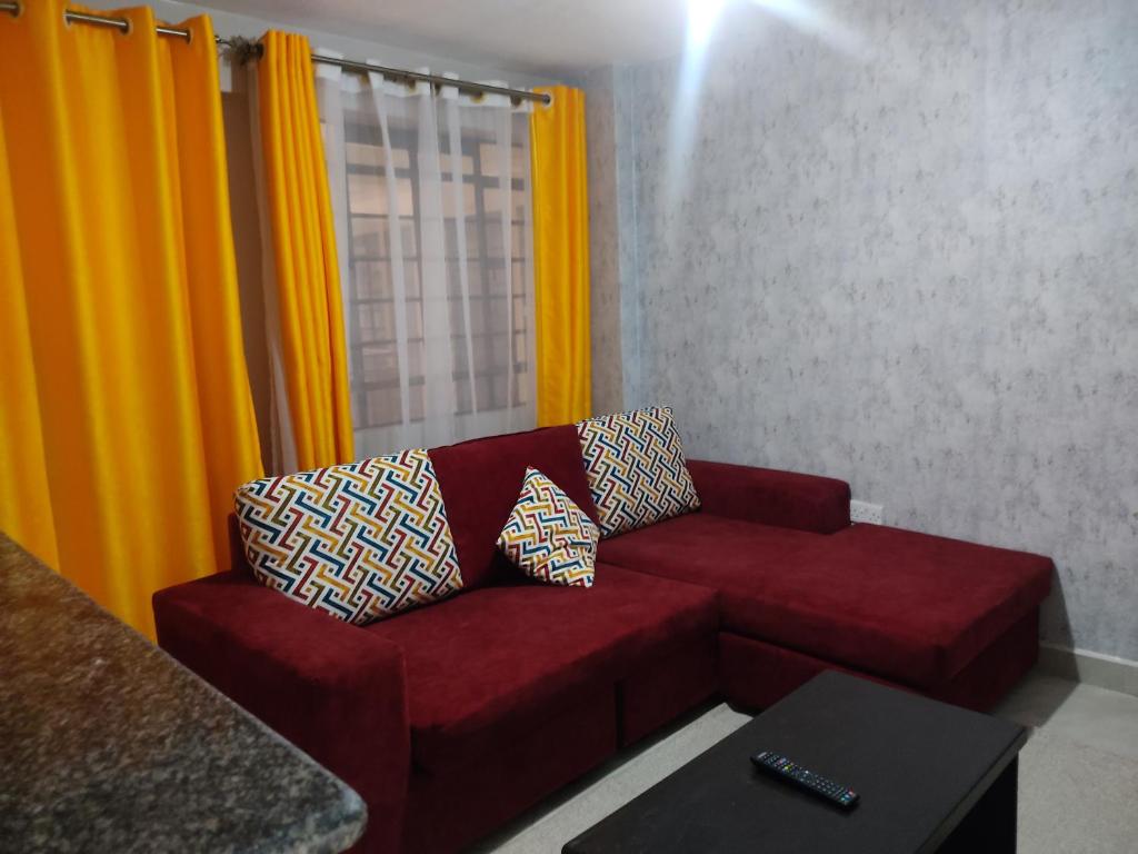 a red couch in a living room with yellow curtains at Sparkle Homes in Nairobi