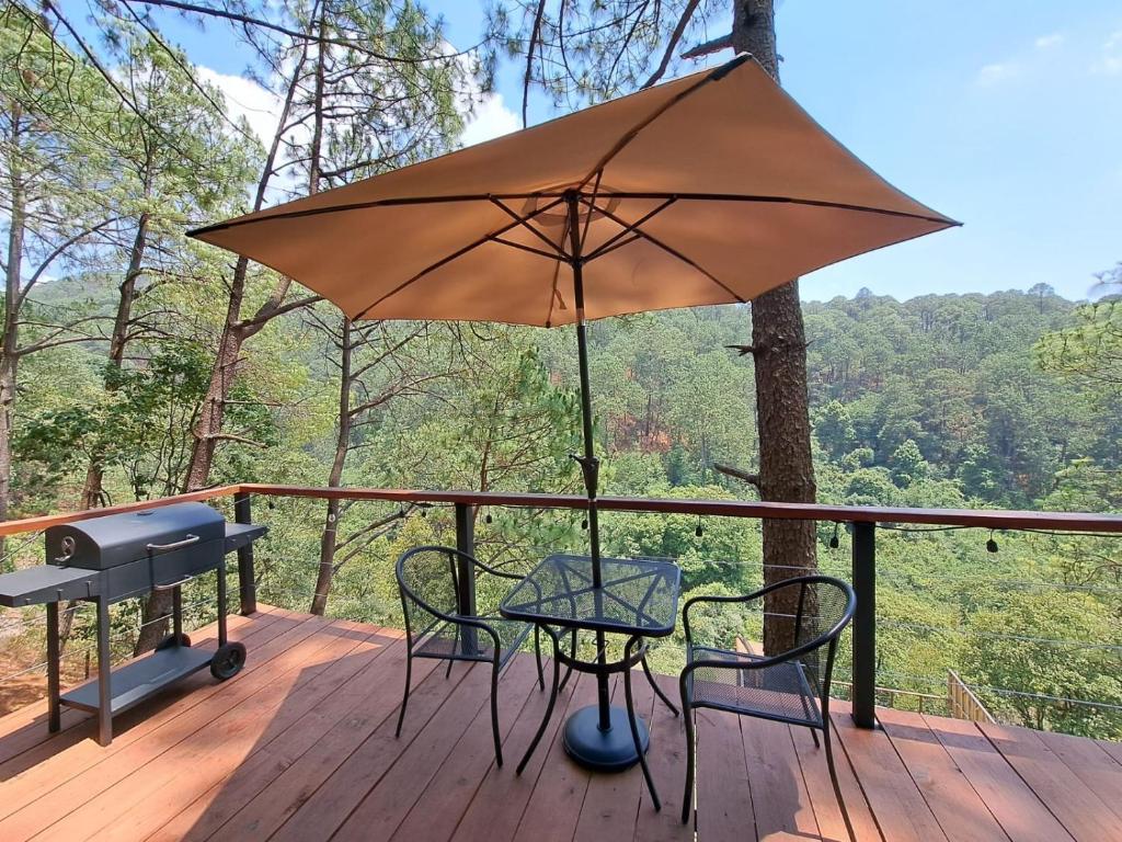 a table and chairs on a deck with an umbrella at Arce Cabañas Mazamitla in Mazamitla