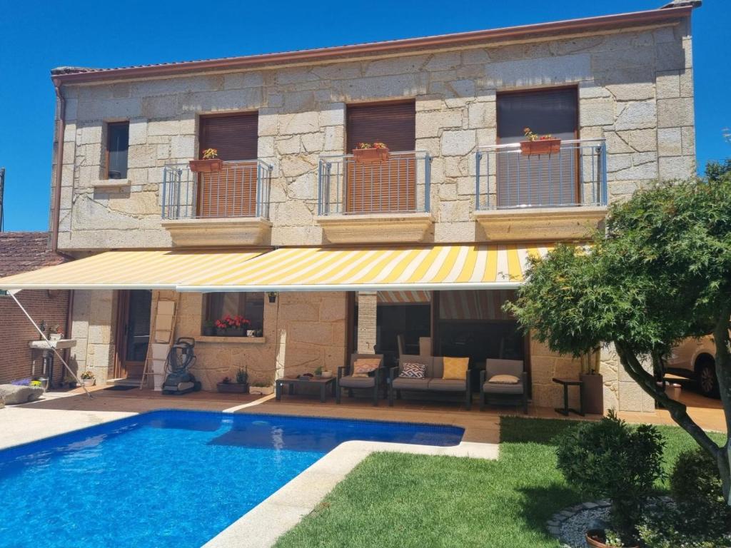 a villa with a swimming pool in front of a building at Chalet Os castaños in Caldas de Reis
