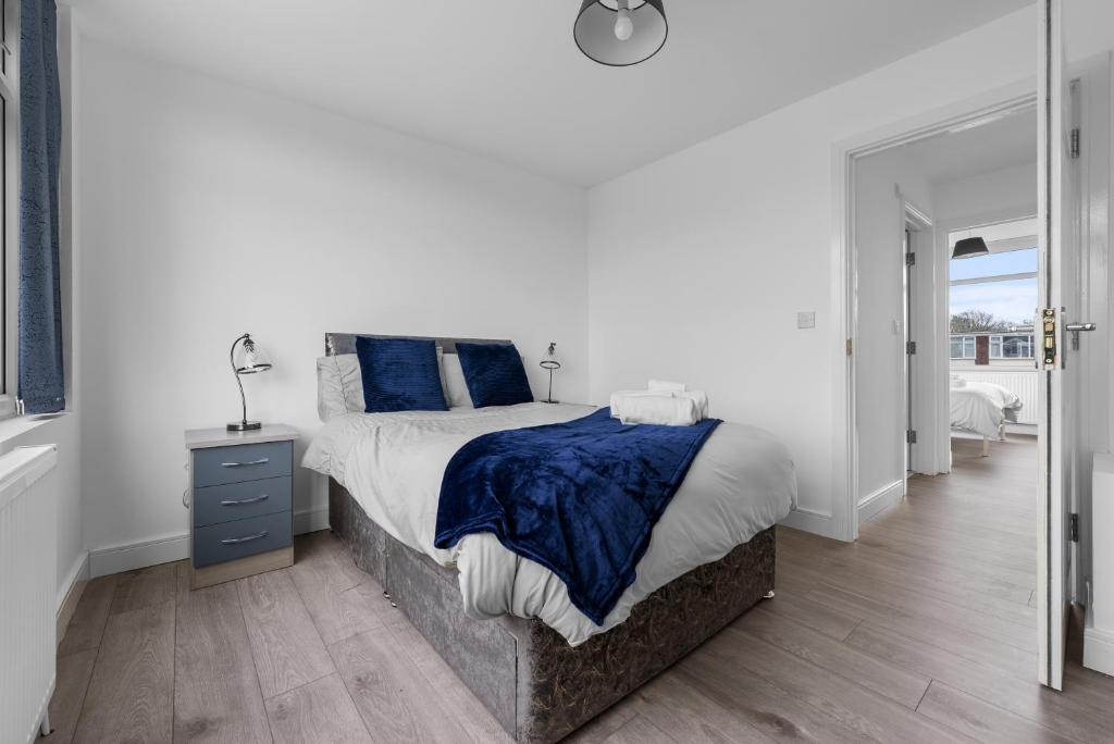 a white bedroom with a large bed with blue pillows at Stylish 3Bedroom House in Prime Leicester Location in Humberstone