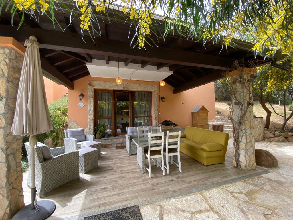 a patio with a table and chairs and an umbrella at Residenza I Ginepri in Domus de Maria