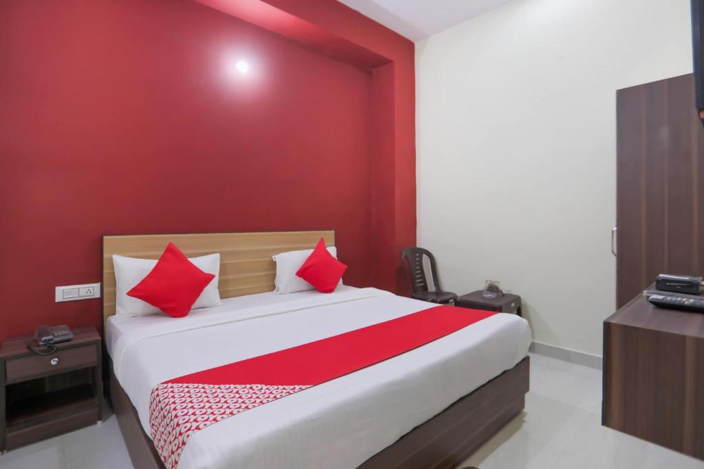a bedroom with a large bed with red walls at OYO Sewa Residency in Faridabad