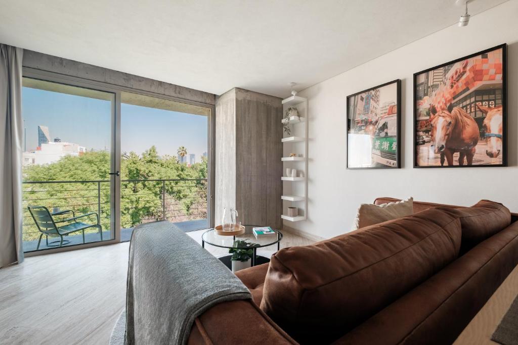 Una sala de estar con un sofá y una ventana grande. en Nido Parque Mexico, en Ciudad de México