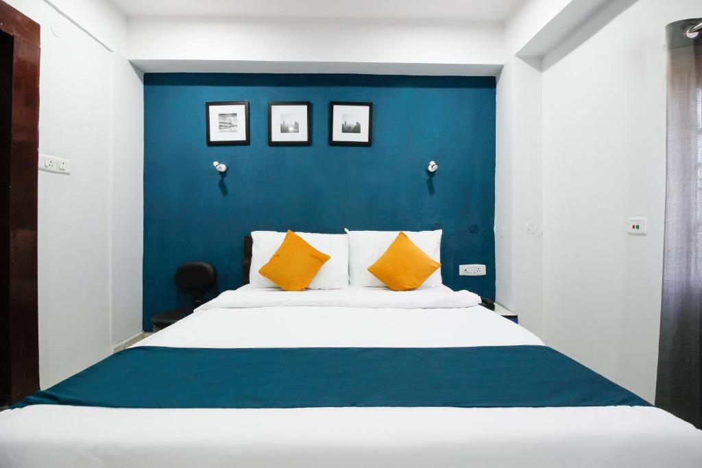una camera da letto con parete blu e un letto con cuscini gialli di SilverKey Hotel Sundari a Nunmāti