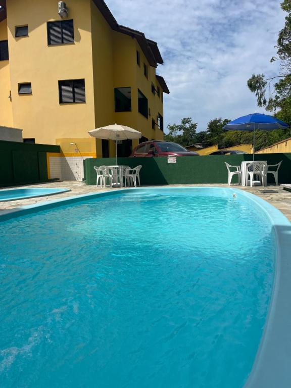 Apartamentos e Flats Praia das Toninhas - Ubatuba في أوباتوبا: مسبح ازرق كبير امام مبنى