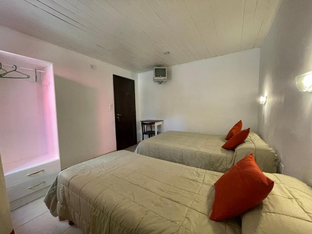 um quarto com 2 camas com almofadas laranja em Habitación céntrica calafate viejo hostel em El Calafate