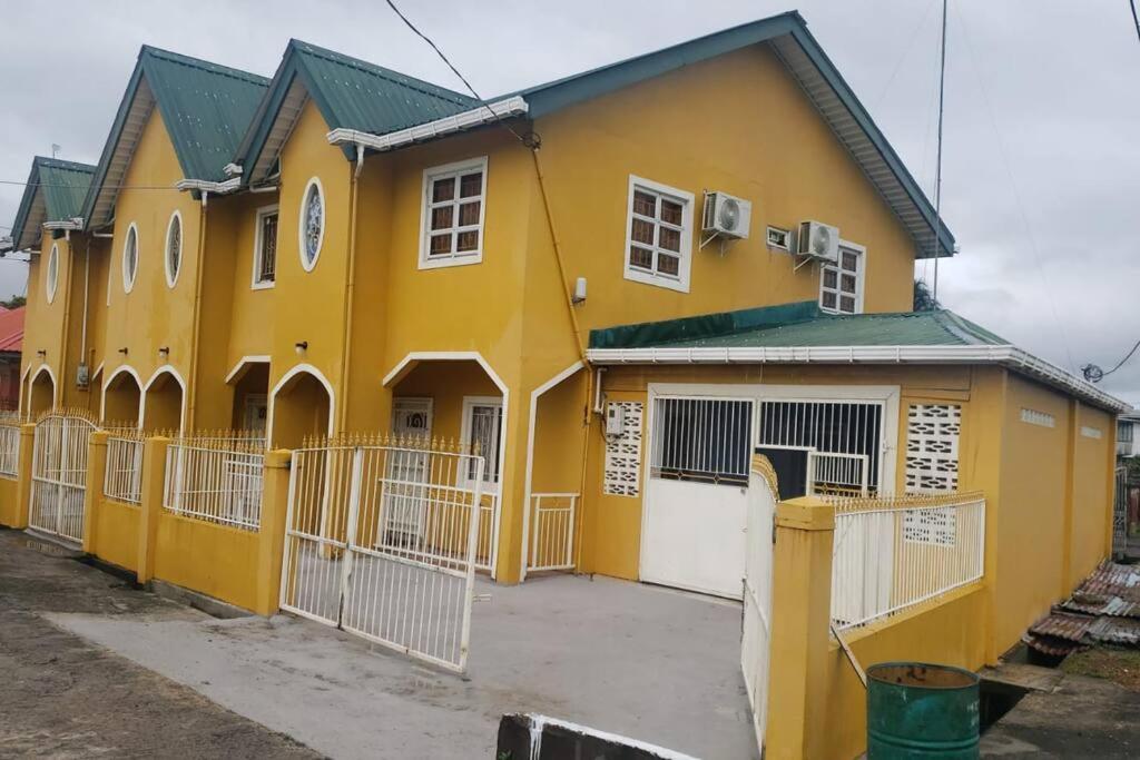 a yellow house with a fence in front of it at Lovely 2 bedroom vacation home with free parking. in Georgetown