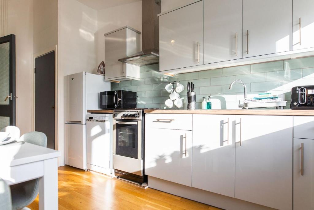 una cocina con armarios blancos y electrodomésticos blancos en Free Parking | Free Wifi | Smart TV en Sketty