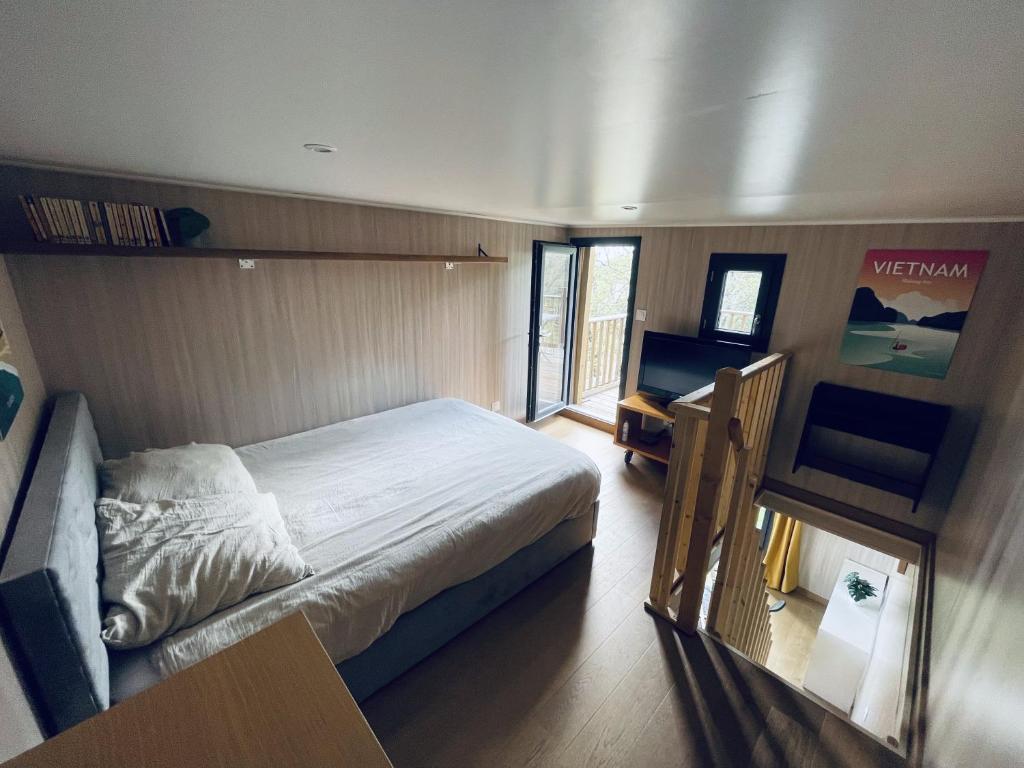 a bedroom with a bed and a desk and a window at Tiny House en lisière de forêt in Les Mages
