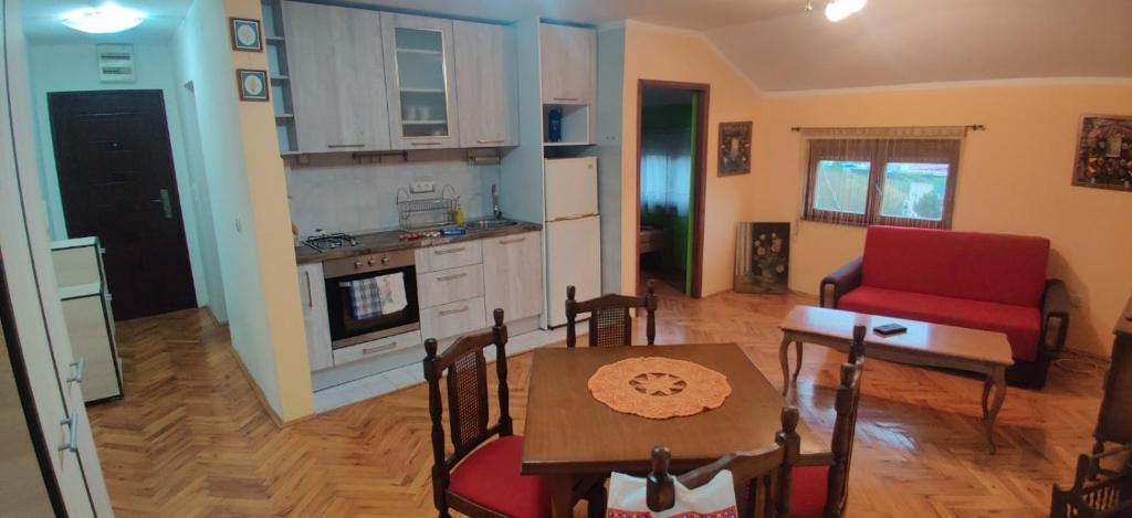 uma cozinha e sala de estar com uma mesa e uma cadeira vermelha em Čardak em Kneževac
