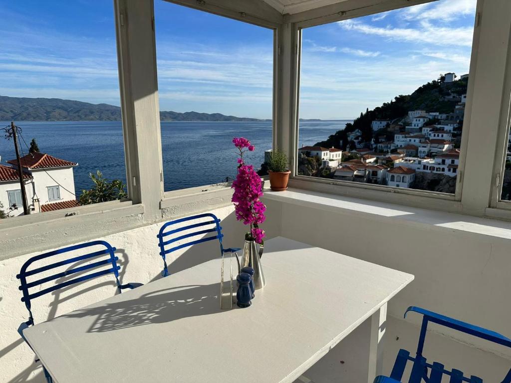 a white table with a vase with flowers on a balcony at Louisa’s View in Hydra