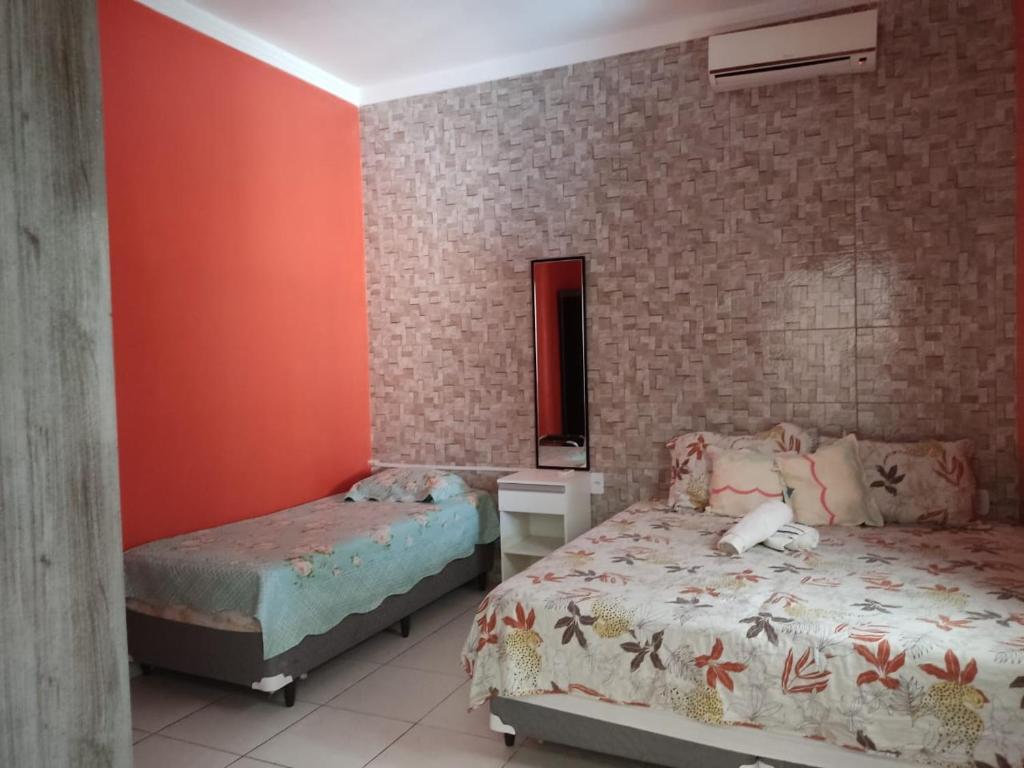 a bedroom with two beds and a brick wall at Casa confortável com piscina compartilhada in Aracaju