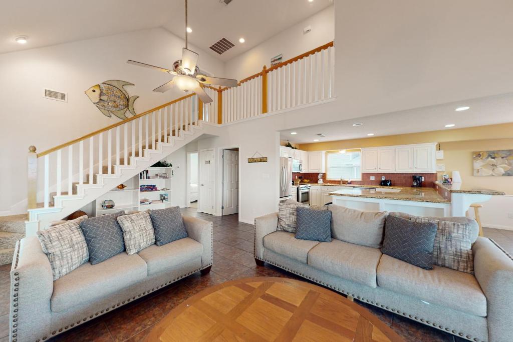 a living room with two couches and a staircase at Sea Breeze in Galveston