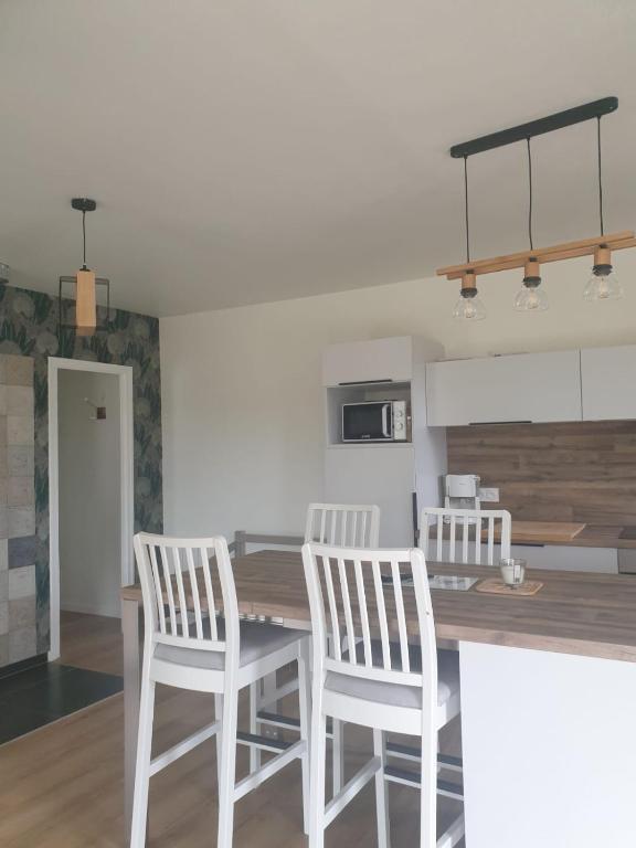 une cuisine avec deux chaises blanches et une table en bois dans l'établissement La petite maison dans la prairie, à Néant-sur-Yvel