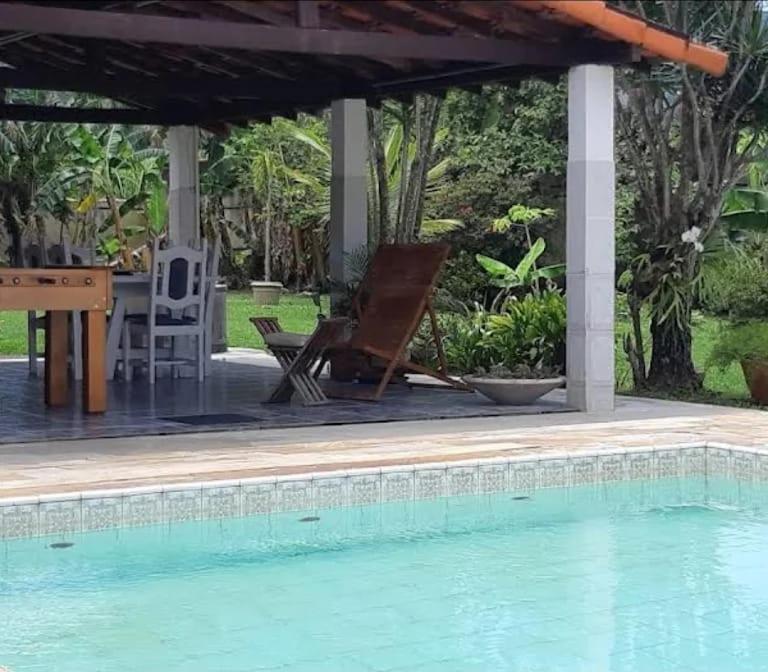 uma cadeira e uma mesa ao lado de uma piscina em Ponta Negra Hospedagem em Maricá