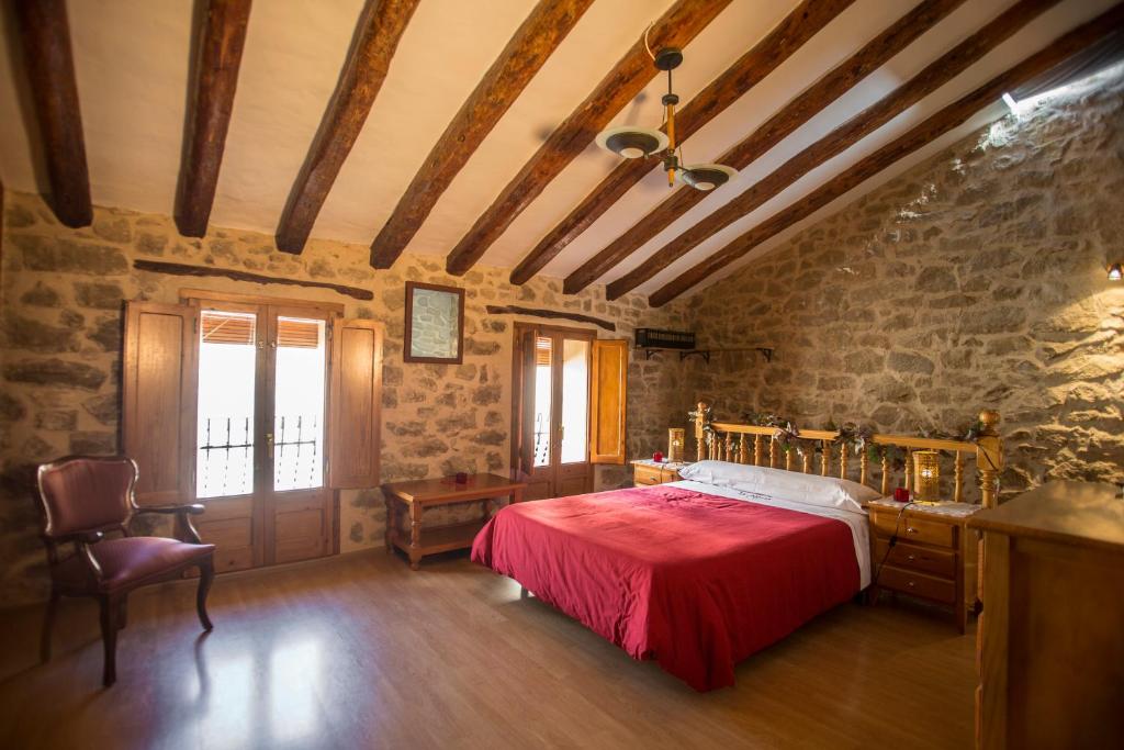 a bedroom with a red bed and a stone wall at Casa rural la Posada Terra Alta Matarraña in Caseras