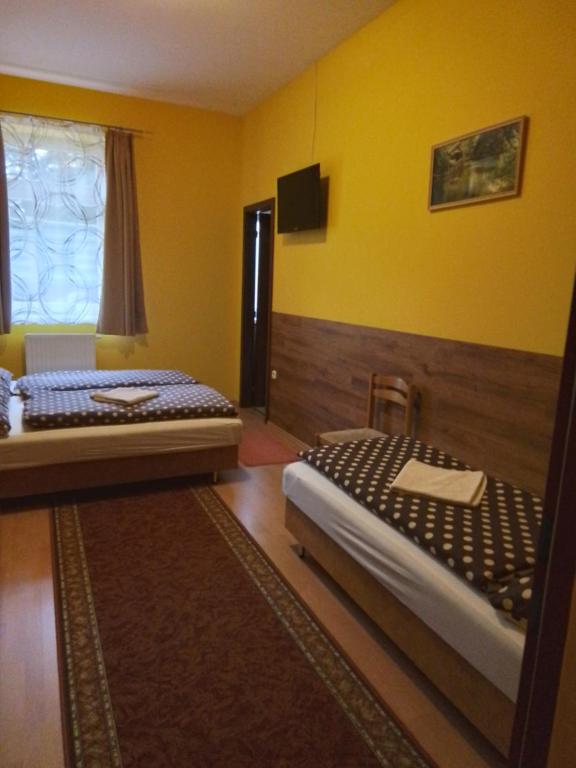 2 Betten in einem Zimmer mit gelben Wänden in der Unterkunft Örségkapuja Vendégház in Csákánydoroszló