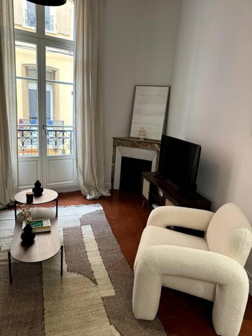 a living room with a white chair and a television at La Réal - Apt 2 chambres rénové in Perpignan