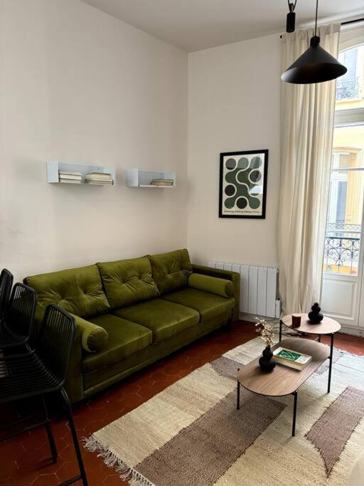 a living room with a green couch and a table at La Réal - Apt 2 chambres rénové in Perpignan