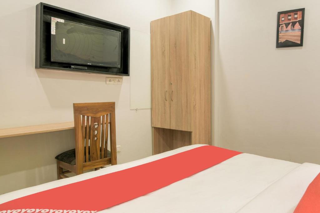 um quarto com uma cama e uma televisão na parede em Collection O Jps Grand Hotel Near Dwarka Metro Station em Nova Deli