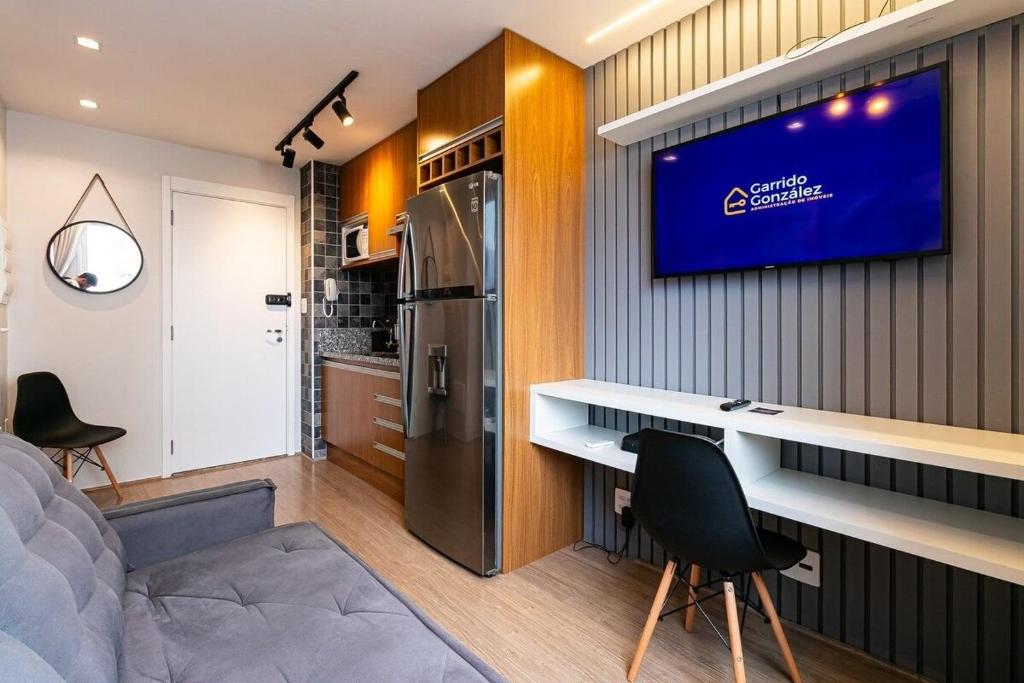 uma cozinha e sala de estar com televisão na parede em Amplo Apartamento no Brás com Piscina/Metrô Brás em São Paulo