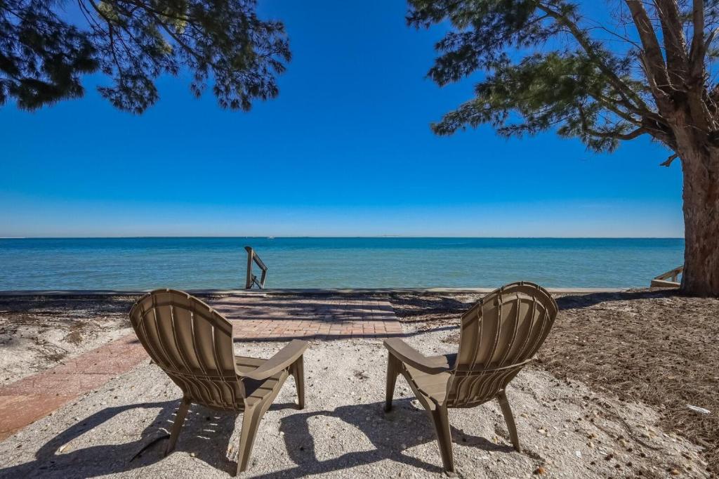 two chairs sitting on the beach near the ocean at Dolphins Run home in Anna Maria