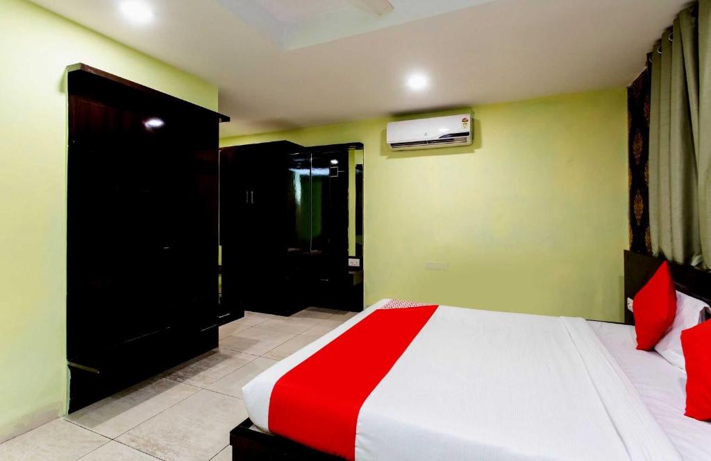 a bedroom with a bed with a red and white blanket at Capital O Swan Paradise in Indore