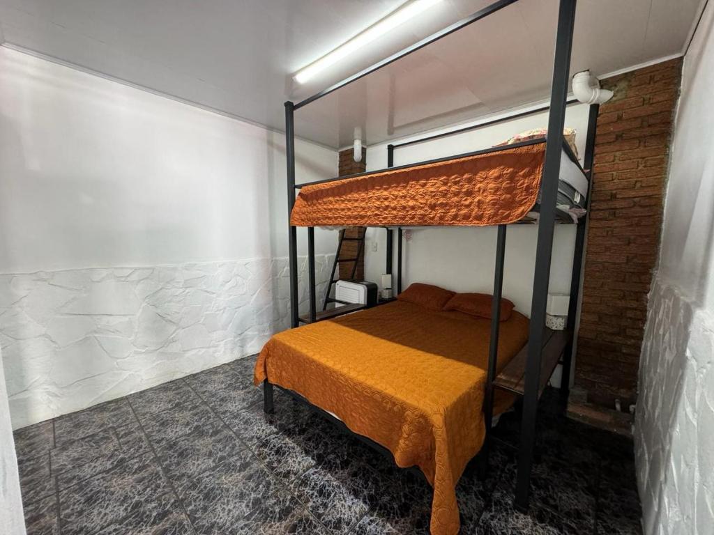1 dormitorio con litera y colcha de color naranja en Casa San Rafael, en Alajuela