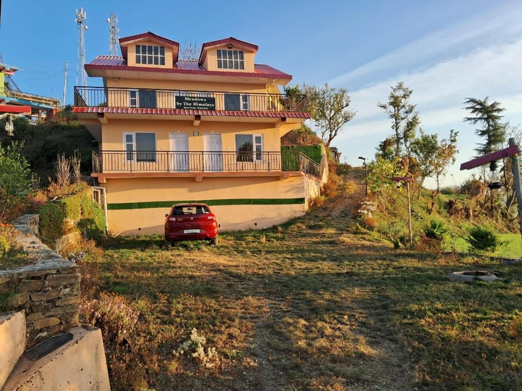 a house with a red car parked in front of it at Meadows By The Himalaya in Shimla